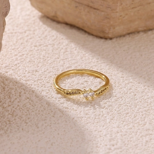 Detail view of 18k gold plated wavy ring with double zircons on a white stone base