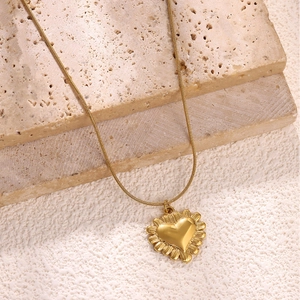 Dettaglio del pendente a cuore in oro 18k con bordo strutturato su catena a serpente