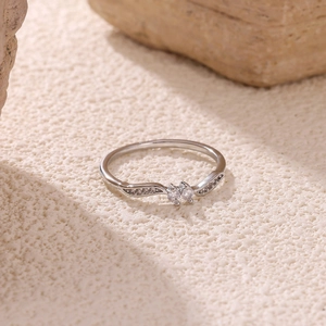 Close-up of dual zircon clusters on polished silver-tone wave ring over rock texture