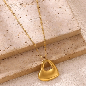 Dettaglio della collana con pendente a cuore in oro lucido su pietre beige testurizzate