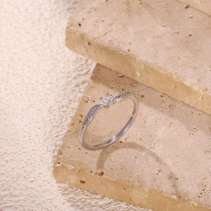 Detail of silver wavy ring with two round zircons on rustic stone textured background