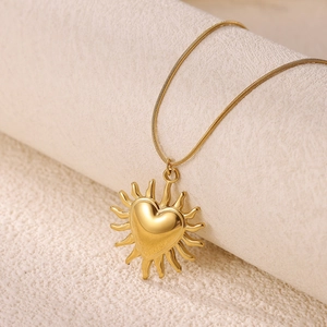 Gros plan d'un pendentif cœur soleil doré 18K sur une chaîne serpent lisse