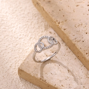 Macro detail of intertwined silver rings with zircon micro-paving on a stone stand