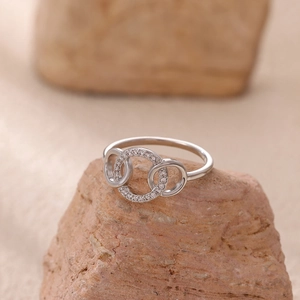Macro detail of intertwined triple silver rings with pavé cubic zirconia on textured rock