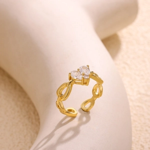 Detail van een gouden opengewerkte ring met twee sprankelende hartvormige zirkonia
