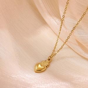 Dettaglio della collana con ciondolo a cuore con bordi perlati su sfondo di tessuto