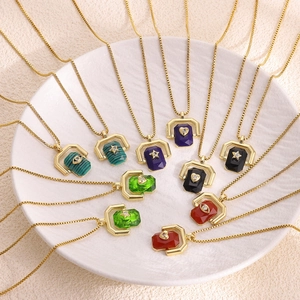 Colorful geometric square pendant necklaces with natural stones and gold chains on a plate