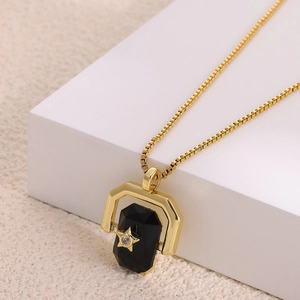 Macro shot of gold necklace featuring black gemstone pendant with star inlay detail
