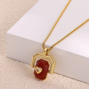 Detail of gold box chain and red rectangular pendant with a sparkling diamond heart