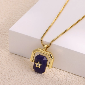 Macro detail of gold U-frame pendant with purple stone, star motif and zircon inlay