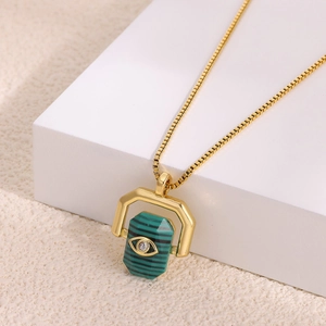 Close-up of golden rotating evil eye pendant with green malachite stone and zircon inlay
