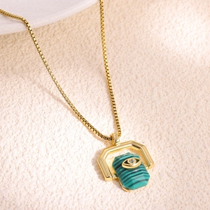Close-up of golden box chain with a hexagonal malachite pendant and evil eye charm