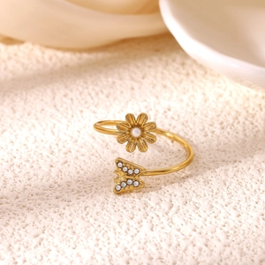 Close-up of gold flower and butterfly open ring with pearl and zirconia details