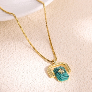 Macro detail of gold box chain and hexagonal green stone pendant with a tiny star