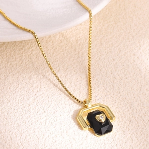 Detailed macro of golden box chain with heart-shaped zircon on black gem pendant