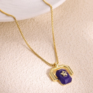 Detailed shot of a gold box chain necklace with a purple gem and star pendant design