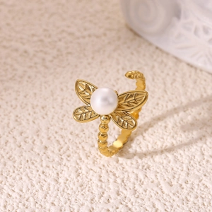 Macro detail of a dragonfly open ring with a white pearl and gold plated wings