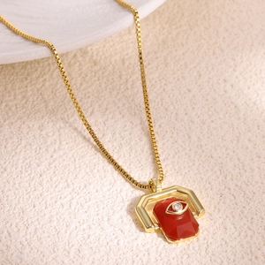 Macro shot of gold box chain necklace featuring a red rectangle stone with evil eye detail