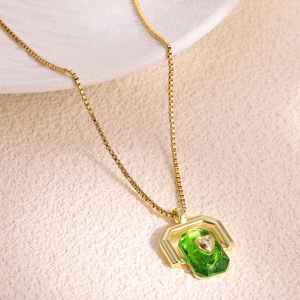 Detail shot of a gold necklace featuring a rectangular green stone with a tiny heart inlay