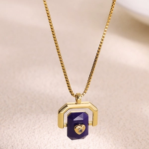 Macro shot of geometric pendant with purple stone and gold heart on box chain necklace