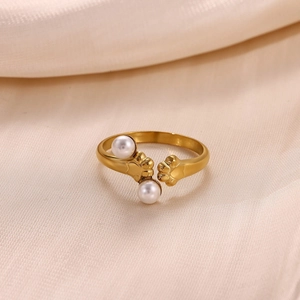 Macro detail of gold-plated cat paw ring with faux pearl on soft silk background
