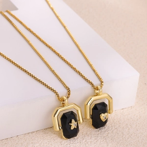 Gold box chain necklace with octagonal black stone pendant featuring star and heart charms