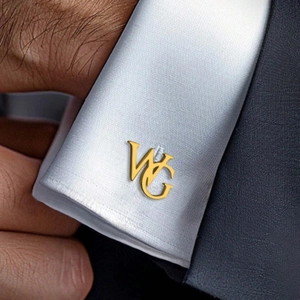 Detailed view of custom gold WG initial cufflinks worn on a white dress shirt cuff