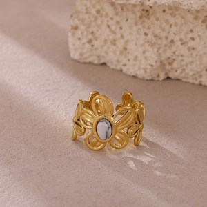 Detalle de anillo de flor vintage con acabado dorado mate y piedra preciosa blanca