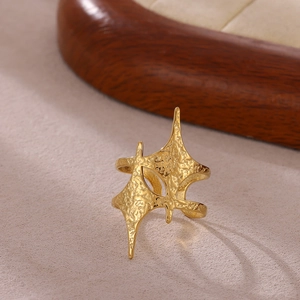 Detalle de anillo de estrella dorado con textura martillada rústica y banda abierta