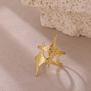 Detalle de anillo en acero dorado con textura martillada y forma de estrella irregular