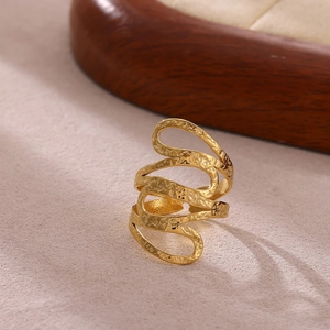 Detalle de anillo dorado ondulado con textura martillada y diseño minimalista de varias capas