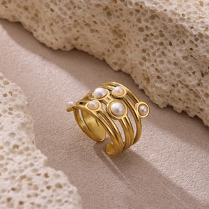 Detalle del anillo multicapa chapado en oro con perlas blancas y acabado de metal cepillado