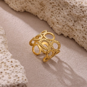 Detalle de anillo de acero dorado con círculos huecos y textura de puntos finos