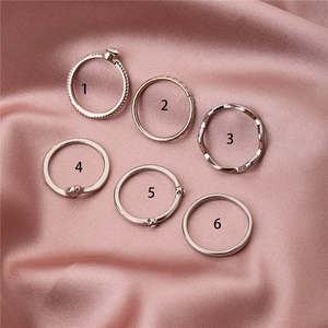 Detaillierte Ansicht des 6-teiligen Silberring-Sets mit Herz- und Wellendesign auf Satin