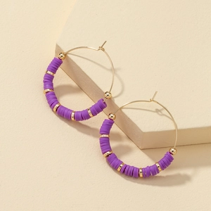 Bohemian gold hoop earrings with purple heishi beads and gold spacer beads on beige stand