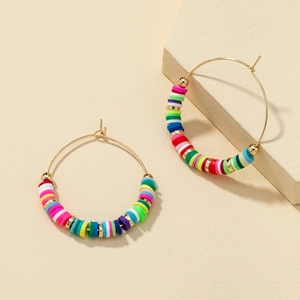 Colorful heishi bead hoop earrings with gold accents on a textured beige display