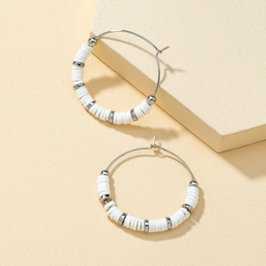 Detailed macro view of bohemian white heishi beads and silver metal beads on hoop earrings