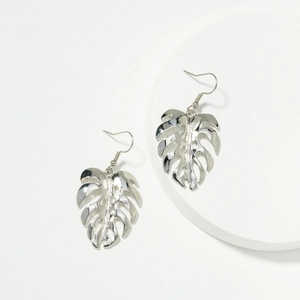 Vue détaillée des boucles d'oreilles feuille de monstera argentées sur support en pierre