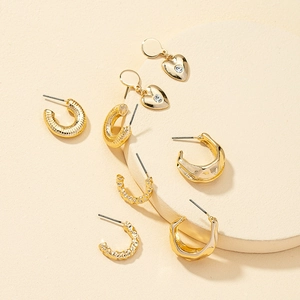 Détail macro d'un ensemble de boucles d'oreilles dorées avec cœurs et créoles texturées
