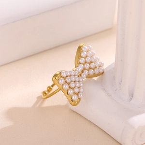 Primer plano de un anillo de lazo bañado en oro de 18k con perlas sobre columna