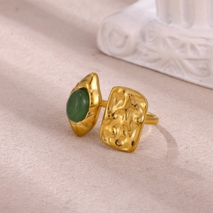 Detailed macro view of gold-plated ring with green gemstone and hammered metal texture