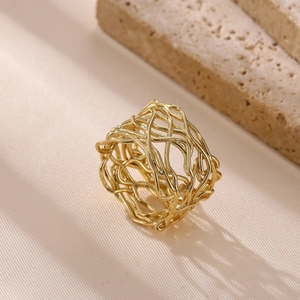 Detailed macro view of a gold-toned bird nest hollow wide band ring on silk fabric