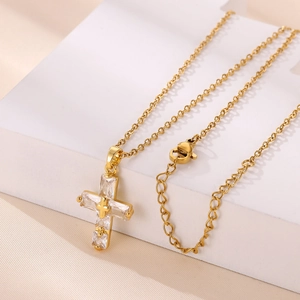 Dettaglio di una collana a croce dorata con pietre di zircone rettangolari e catena regolabile