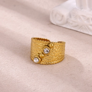 Macro detail of gold plated textured wide ring with cubic zirconia stones and metal beads