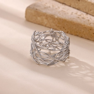 Macro shot of irregular silver stainless steel hollow wide ring on a textured stone