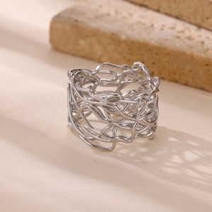 Macro shot of silver bird's nest style woven ring on textured stone base and beige fabric