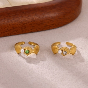 Detailed macro view of golden shell-shaped open rings with zircon and pearl accents