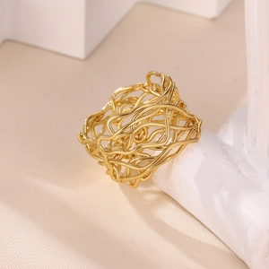 Macro shot of gold wide hollow ring with irregular wire mesh design on marble stand