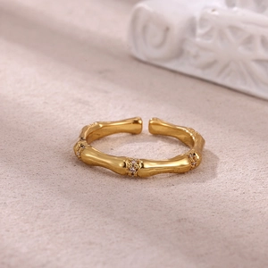 Close-up of gold bamboo ring with micro-set zircons on a textured minimalist background