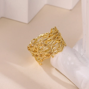 Macro detail of golden irregular branch-like hollowed ring on cream textured surface